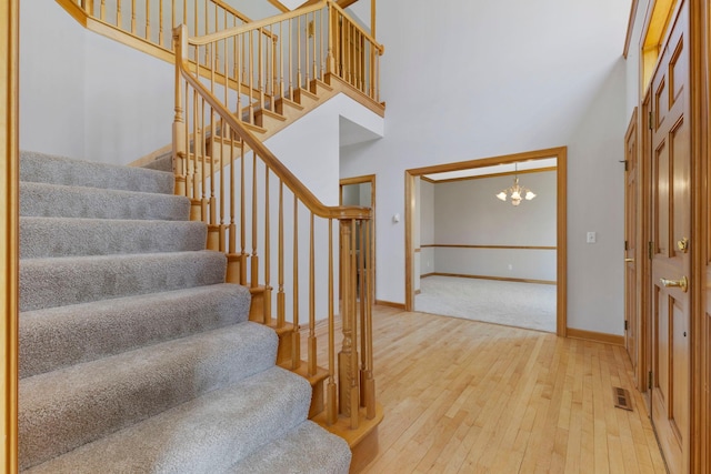 3088 Canyon Rd, Chaska, MN 55318 - staircase featuring visible vents, hardwood / wood-style floors, baseboards, a high ceiling, and a notable chandelier