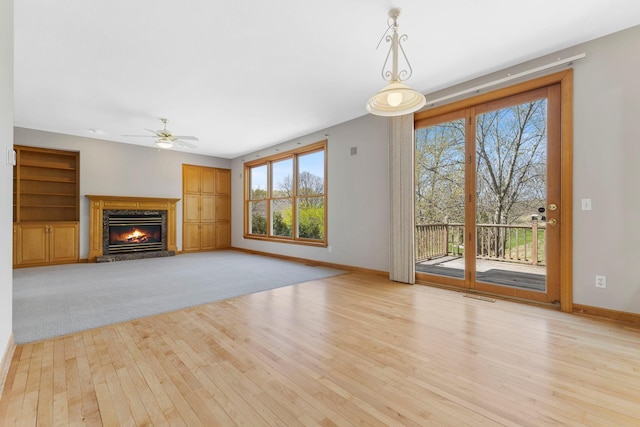 3088 Canyon Rd, Chaska, MN 55318 - unfurnished living room featuring a glass covered fireplace, a ceiling fan, baseboards, visible vents, and hardwood / wood-style flooring