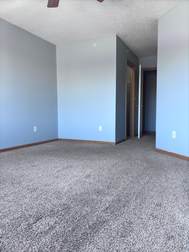 carpeted empty room with baseboards, a ceiling fan, and a textured ceiling
