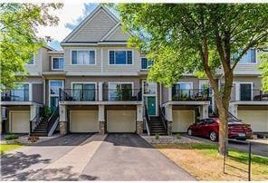 townhome / multi-family property featuring stairs, a garage, and driveway