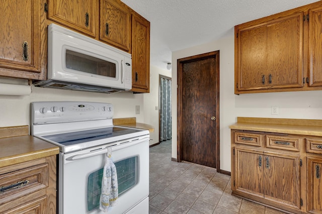 224 Spring St, Holdingford, MN 56340 - kitchen with brown cabinetry, white appliances, light tile patterned flooring, and a textured ceiling