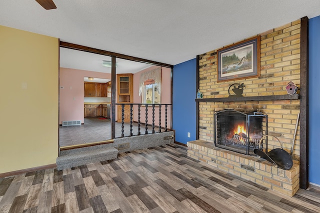 224 Spring St, Holdingford, MN 56340 - unfurnished living room with visible vents, wood finished floors, baseboards, and a brick fireplace