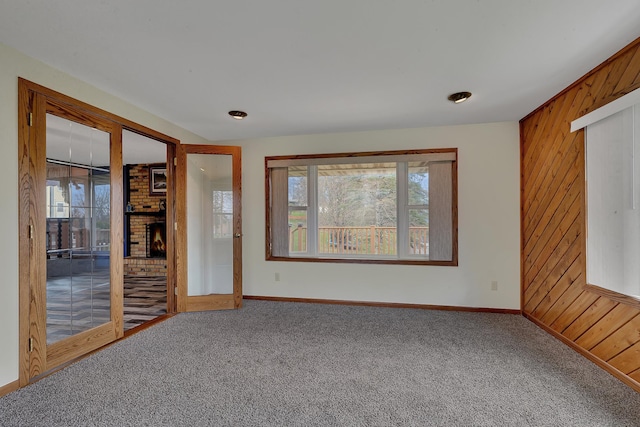 224 Spring St, Holdingford, MN 56340 - carpeted spare room featuring a fireplace, wood walls, and a wealth of natural light