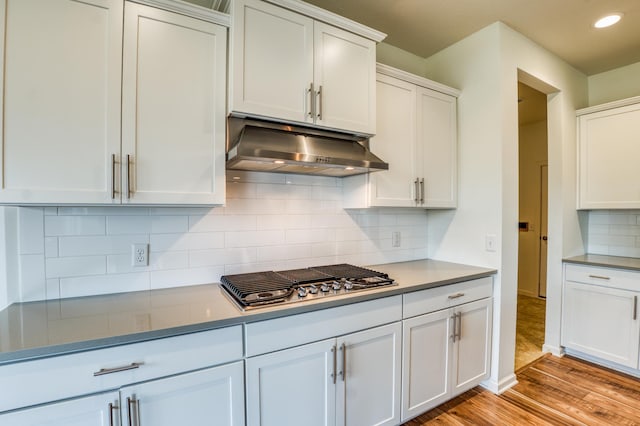 15637 Eddy Creek Way, Apple Valley, MN 55124 - kitchen with ventilation hood, stainless steel gas stovetop, light wood-style flooring, white cabinets, and tasteful backsplash