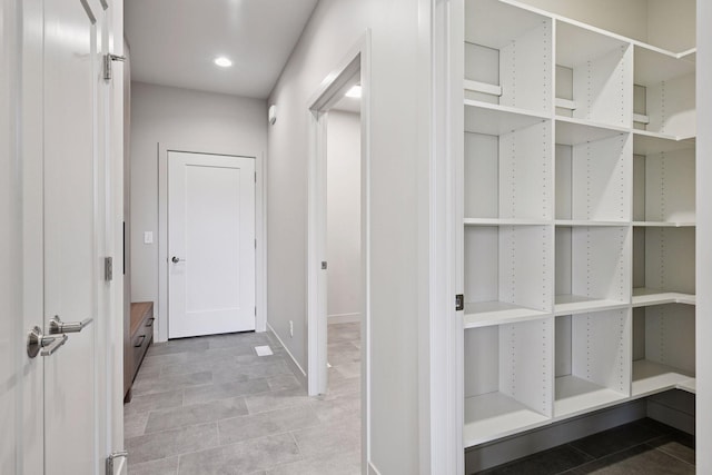 hall featuring baseboards, recessed lighting, and light tile patterned floors
