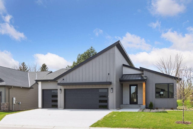 contemporary house with a front yard, metal roof, a standing seam roof, concrete driveway, and an attached garage