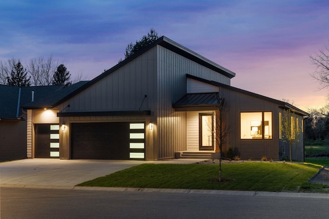 contemporary home featuring a lawn, a garage, and driveway