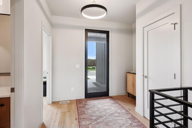 doorway to outside featuring light wood-style floors, baseboards, and visible vents