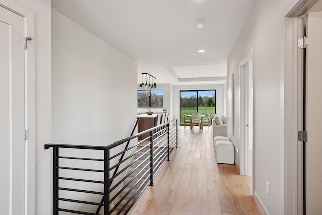 corridor with baseboards, recessed lighting, light wood-style flooring, and an upstairs landing