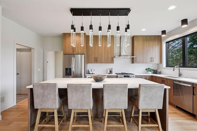 kitchen featuring stainless steel appliances, brown cabinetry, a sink, and modern cabinets