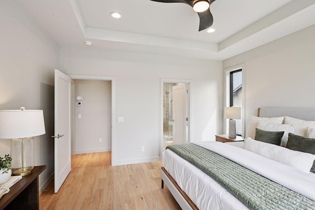 bedroom featuring light wood-type flooring, recessed lighting, a raised ceiling, and baseboards