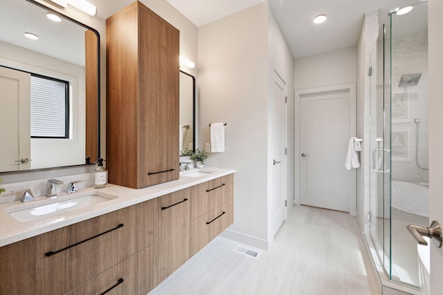 full bathroom featuring visible vents, a sink, a stall shower, and double vanity