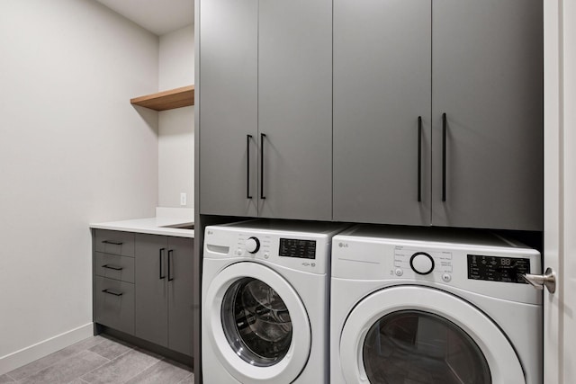 clothes washing area featuring cabinet space, separate washer and dryer, and baseboards