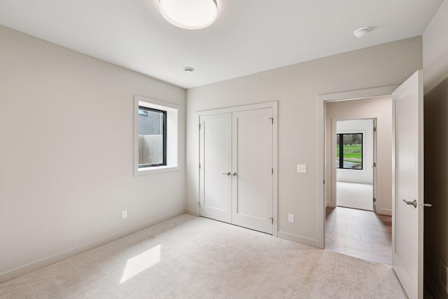 unfurnished bedroom featuring baseboards, carpet, and a closet