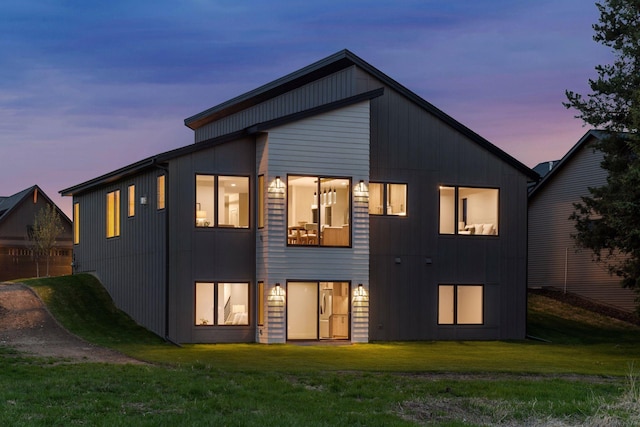 back of house at dusk featuring a yard