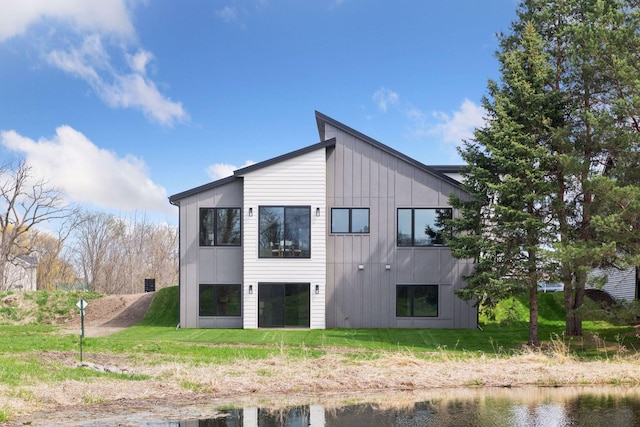 back of house featuring a lawn, board and batten siding, and a water view