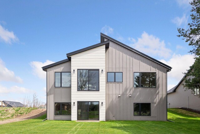 rear view of property featuring board and batten siding and a yard