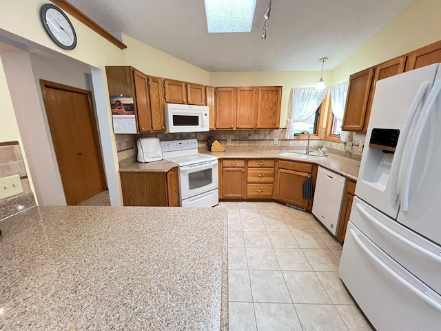kitchen featuring a sink, brown cabinetry, white appliances, and tasteful backsplash