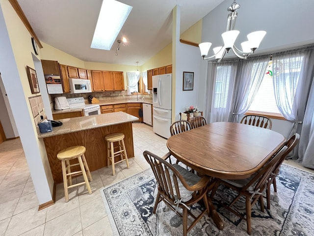 dining area featuring light tile patterned flooring, a notable chandelier, and vaulted ceiling with skylight