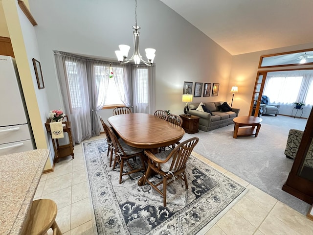 dining room featuring light carpet, a chandelier, light tile patterned flooring, and high vaulted ceiling