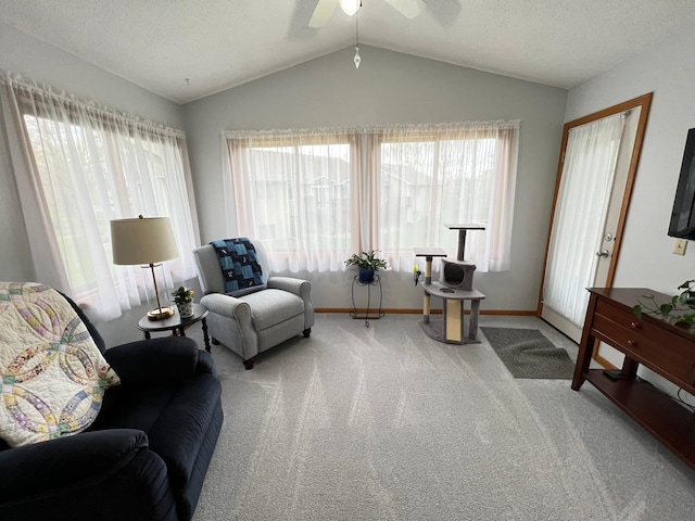 sitting room with ceiling fan, lofted ceiling, carpet floors, and a healthy amount of sunlight