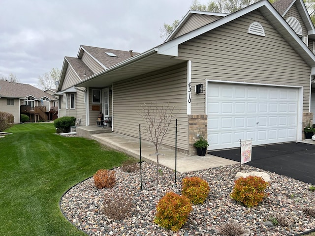 view of side of home with a garage, a lawn, and aphalt driveway
