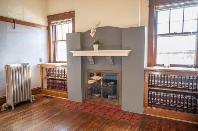 560 7th St, Red Wing, MN 55066 - living room with hardwood / wood-style floors, radiator heating unit, a fireplace with flush hearth, and visible vents