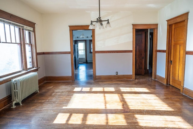 560 7th St, Red Wing, MN 55066 - unfurnished dining area featuring an inviting chandelier, wood finished floors, baseboards, and radiator heating unit
