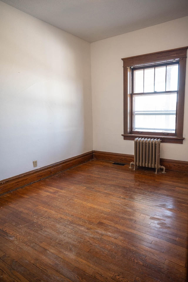 560 7th St, Red Wing, MN 55066 - empty room with dark wood-style flooring, radiator, and baseboards