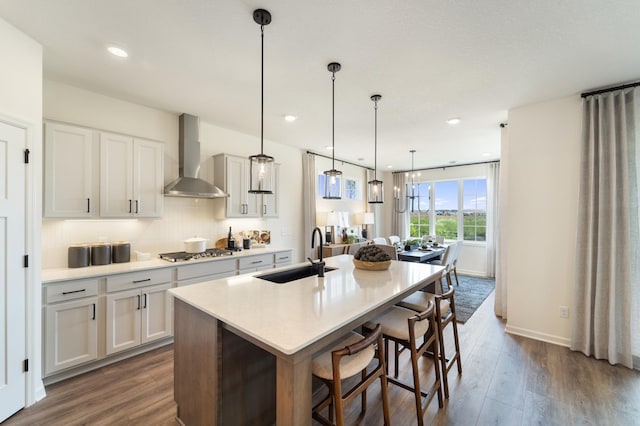 11280 Niagara Ln N, Dayton, MN 55369 - kitchen featuring wall chimney range hood, a sink, stainless steel gas cooktop, dark wood-style floors, and a kitchen island with sink