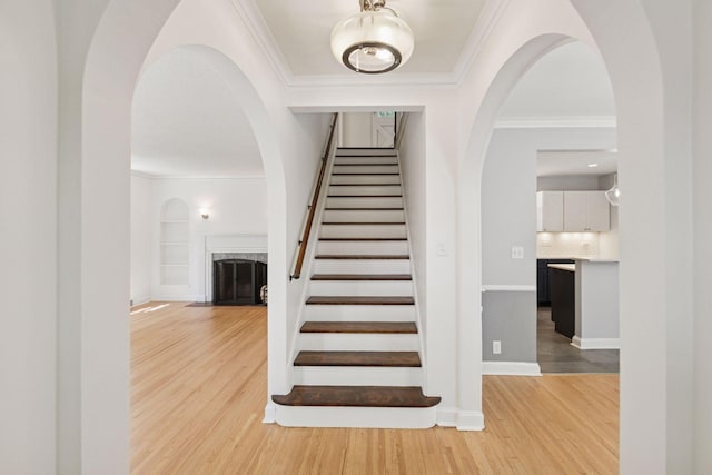 5620 Stevens Ave, Minneapolis, MN 55419 - staircase featuring arched walkways, ornamental molding, wood finished floors, a fireplace with flush hearth, and built in features