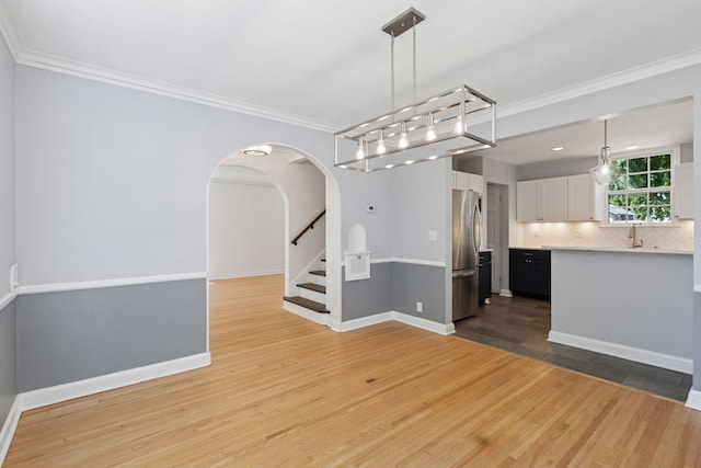 5620 Stevens Ave, Minneapolis, MN 55419 - unfurnished dining area with light wood-style flooring, arched walkways, crown molding, and stairway