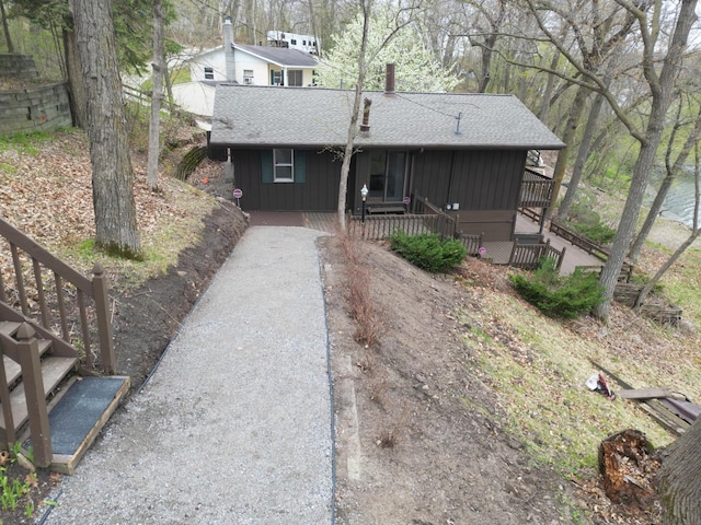 view of front facade with board and batten siding, driveway, a shingled roof, and covered porch