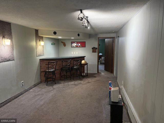 carpeted dining room featuring a bar, a textured ceiling, and baseboards