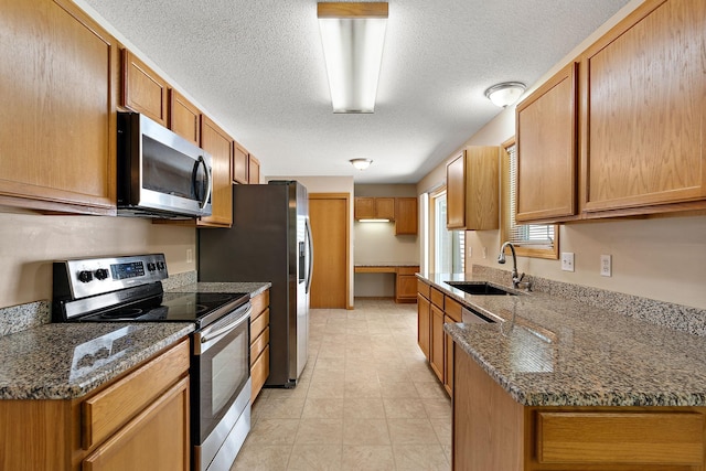 10773 Tamarack Cir NW, Coon Rapids, MN 55433 - kitchen featuring stainless steel appliances, a sink, a textured ceiling, dark stone counters, and brown cabinetry