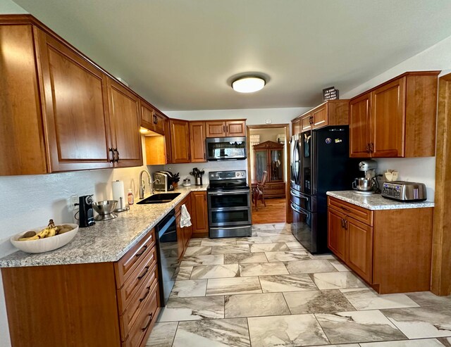 kitchen featuring brown cabinetry, a sink, and black appliances