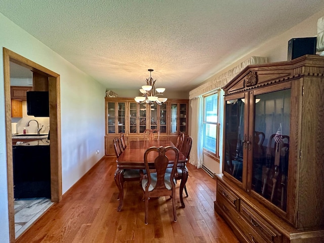 dining room featuring wood finished floors, a textured ceiling, and a chandelier