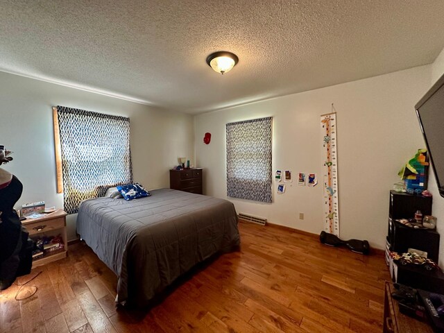bedroom featuring wood-type flooring, a textured ceiling, and visible vents