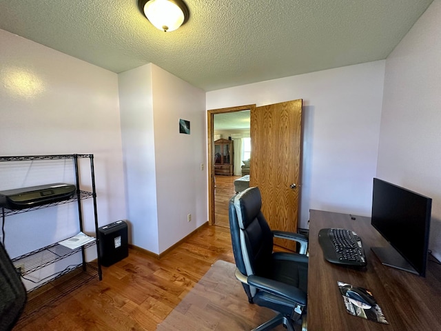 office area featuring baseboards, a textured ceiling, and wood finished floors