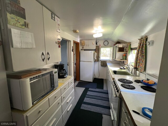 1219 Shore Dr, Luck, WI 54853 - kitchen with white appliances, vaulted ceiling, a sink, light countertops, and white cabinetry