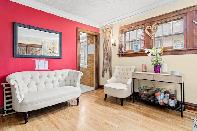 sitting room featuring crown molding, baseboards, a textured ceiling, and wood finished floors