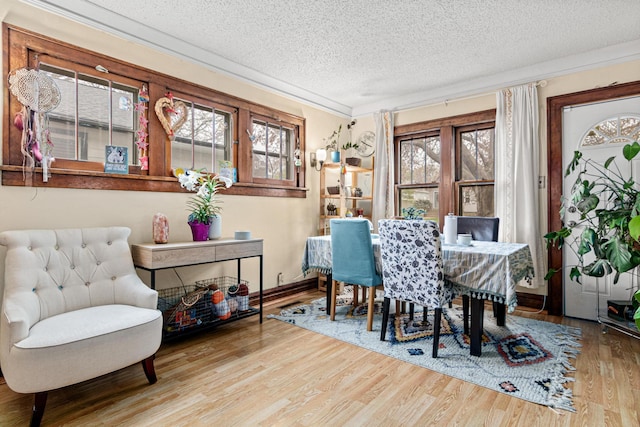dining area featuring crown molding, a textured ceiling, baseboards, and wood finished floors