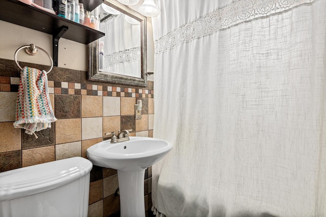 bathroom featuring backsplash, toilet, and tile walls