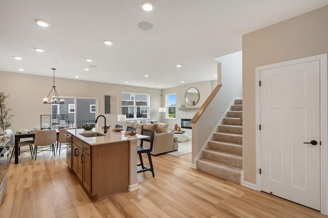 6758 Wildflower Way, Minnetrista, MN 55331 - kitchen with a sink, brown cabinetry, light wood-type flooring, a kitchen island with sink, and recessed lighting