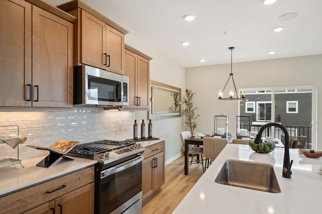 6758 Wildflower Way, Minnetrista, MN 55331 - kitchen with appliances with stainless steel finishes, light countertops, decorative backsplash, light wood finished floors, and a sink