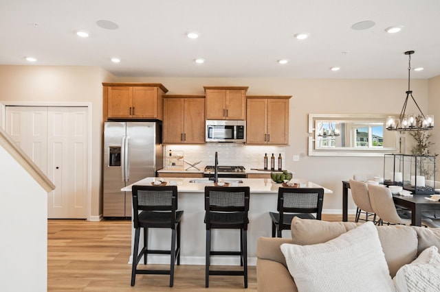 6758 Wildflower Way, Minnetrista, MN 55331 - kitchen with appliances with stainless steel finishes, open floor plan, light countertops, light wood-style flooring, and backsplash