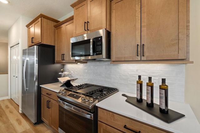6758 Wildflower Way, Minnetrista, MN 55331 - kitchen with appliances with stainless steel finishes, light wood-type flooring, decorative backsplash, light countertops, and brown cabinetry