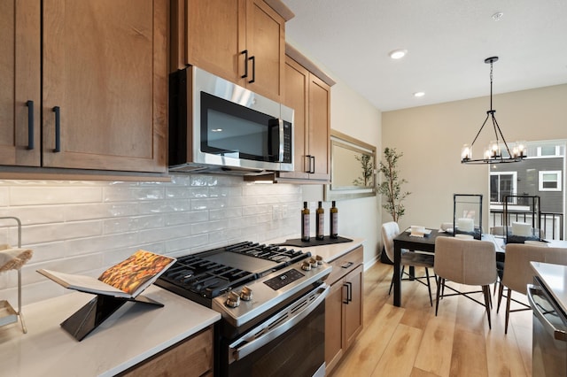 6758 Wildflower Way, Minnetrista, MN 55331 - kitchen with appliances with stainless steel finishes, tasteful backsplash, light wood-style floors, a chandelier, and light countertops