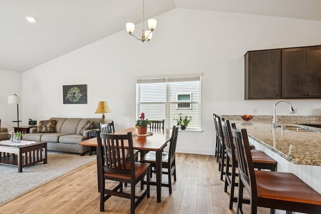 dining space with light wood-type flooring, high vaulted ceiling, and a chandelier