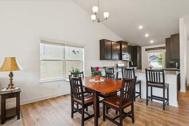 dining space with light wood-type flooring, a chandelier, high vaulted ceiling, baseboards, and recessed lighting